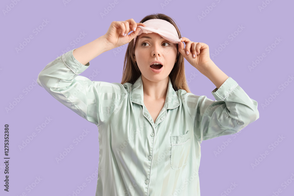 Young woman in pajamas with sleeping mask on lilac background Young woman in pajamas with sleeping mask on lilac background