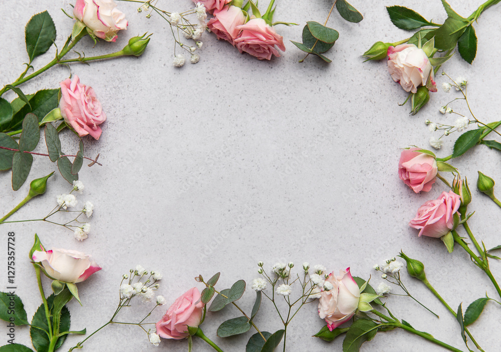 Pink roses and eucalyptus leaves creating a frame on a gray background Pink roses and eucalyptus leaves creating a frame on a gray background