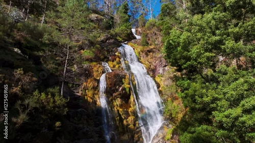 Waterfall Flowing In Lush Green Forest. ascending drone shot photo