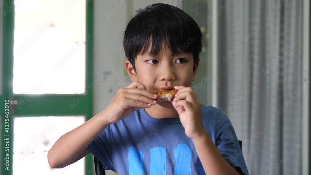 Asian child boy eat fried chicken food while watching television at home. Asian child boy eat fried chicken food while watching television at home.