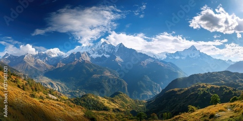 Majestic panoramic view of a mountain range with peaks under a blue sky featuring white clouds and vibrant green valleys in the foreground.