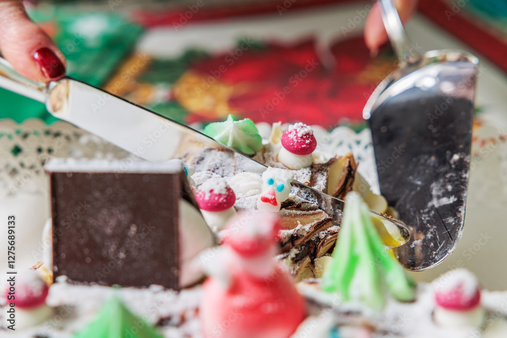 mano di una donna adulta irriconoscibile mentre taglia una fetta di un tronchetto di natale