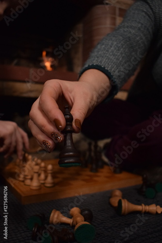 A young parent and child enjoy cozy leisure time by the fireplace, embracing the warmth and comfort of winter time indoors. Hygge concept. Family bonds and shares precious moments together t home