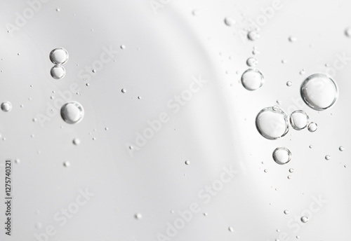 Transparent cosmetic texture with bubbles on gray background front view. Beauty background with care gel.