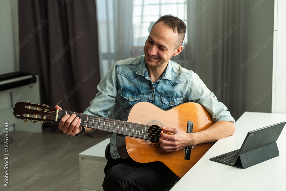 Obraz premium Caucasian man remotely teaches guitar playing on the laptop. Online music training