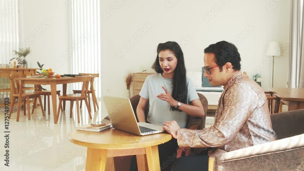 Two professionals discussing work on a laptop in a modern home office. Remote work, collaboration, small business, freelancing, and digital marketing concept in a cozy workspace. Slow motion 4k video. Two professionals discussing work on a laptop in a modern home office. Remote work, collaboration, small business, freelancing, and digital marketing concept in a cozy workspace. Slow motion 4k video.