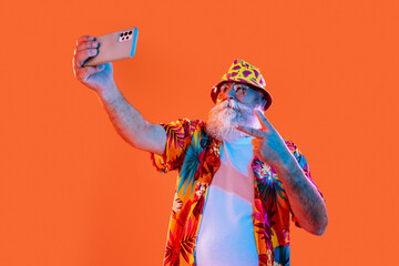Senior old man with gray beard wearing hawaiian shirt portrait in studio - Funny stylish older male adult tourist with cool style, concepts about elderly and lifestyle