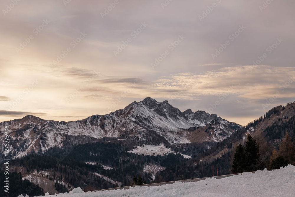 catena montuosa nelle alpi delle montagne innevate del nord Italia, con cielo nuvoloso, in inverno, al tramonto