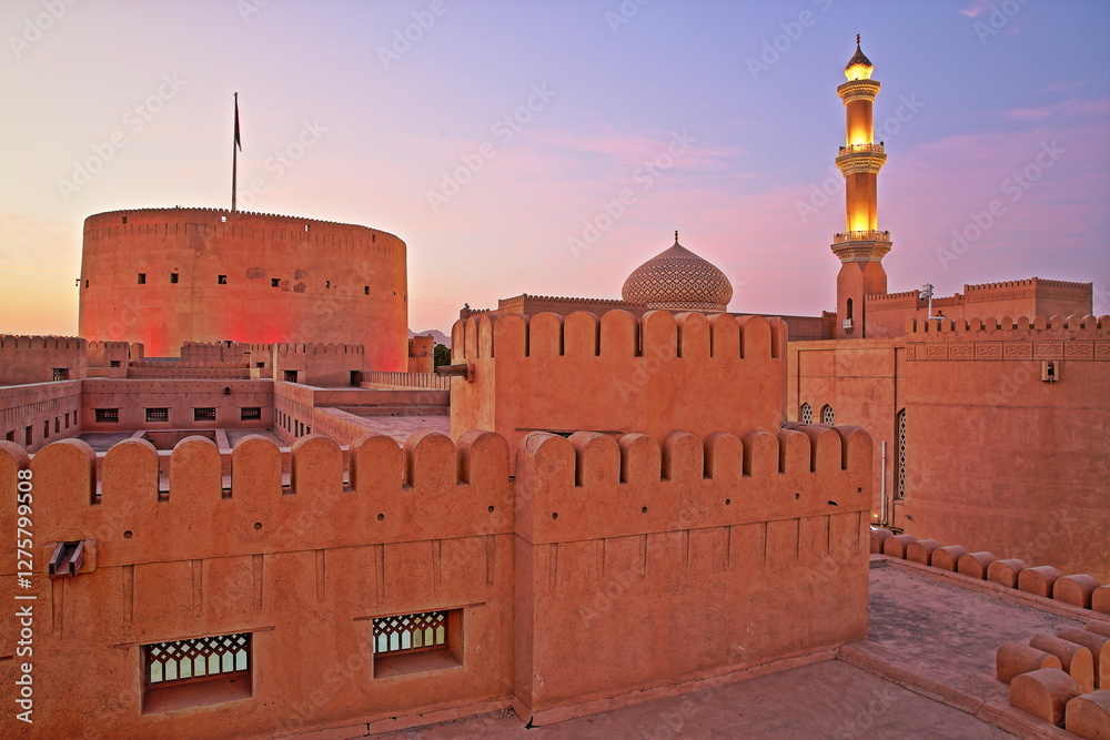 The impressive Nizwa fort in Nizwa, Al Dakhiliyah, Oman, with the Mosque and its minaret on the right. Picture taken during the blue hour