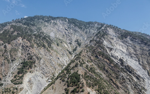 A low-angle shot of a mountain with a clear blue sky in the background.