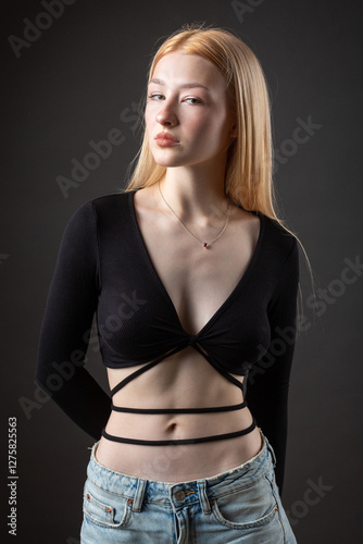 Portrait of a blonde woman with freckles in a sexy top and denim shorts in a studio.
