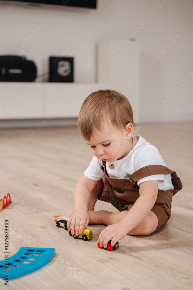 A 2-year-old child in brown overalls plays with educational toys at home, exploring and learning through play A 2-year-old child in brown overalls plays with educational toys at home, exploring and learning through play