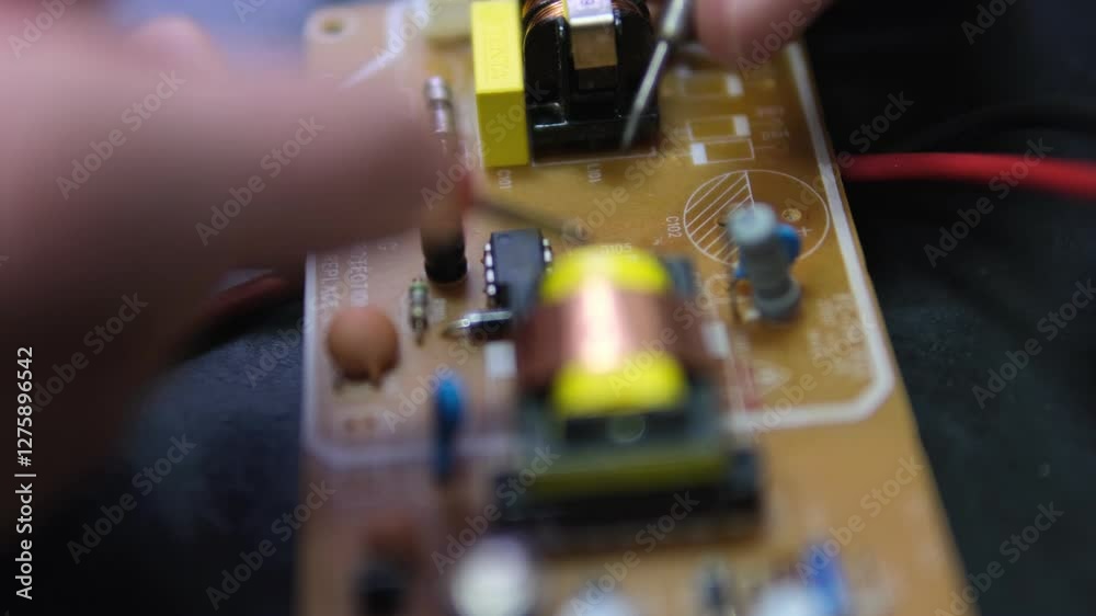 Electrician's hands testing a circuit board with a multimeter, measuring voltage and diagnosing electronic components.