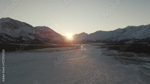 Aerial View Of Mountains And Frozen River In Winter Covered With Snow At Sunrise. photo