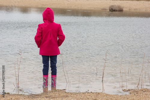 Rear view of child standing in water in wellingtons photo