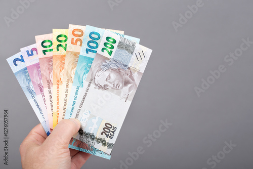 Brazilian money in the hand on a gray background.