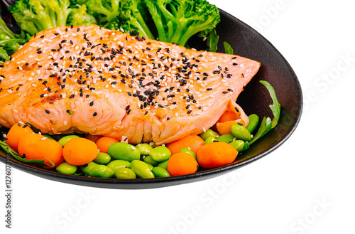 Delicious salmon fillet served with fresh vegetables on a plate photo