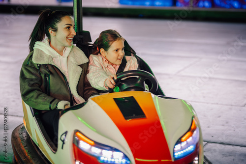 Mother and daughter enjoying bumper car ride at amusement park