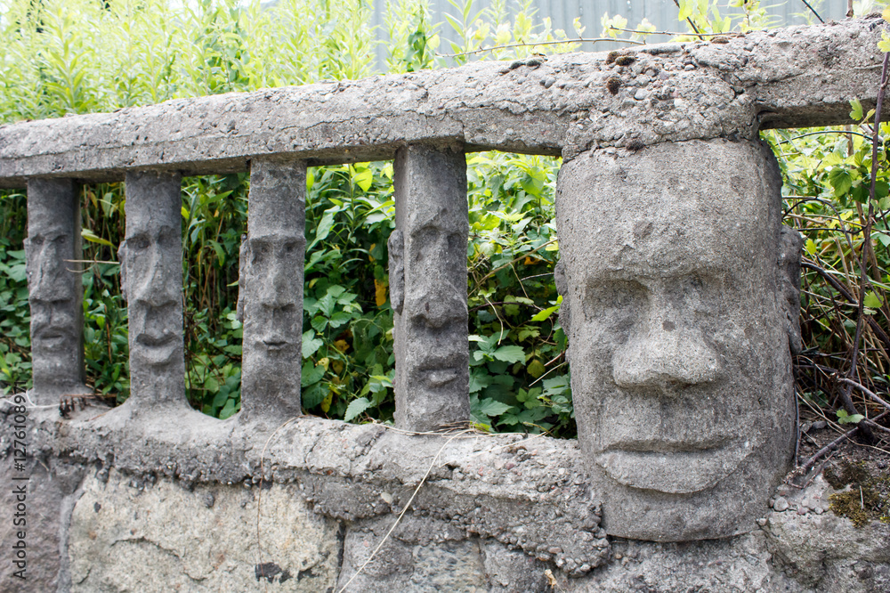 stone fence with human faces