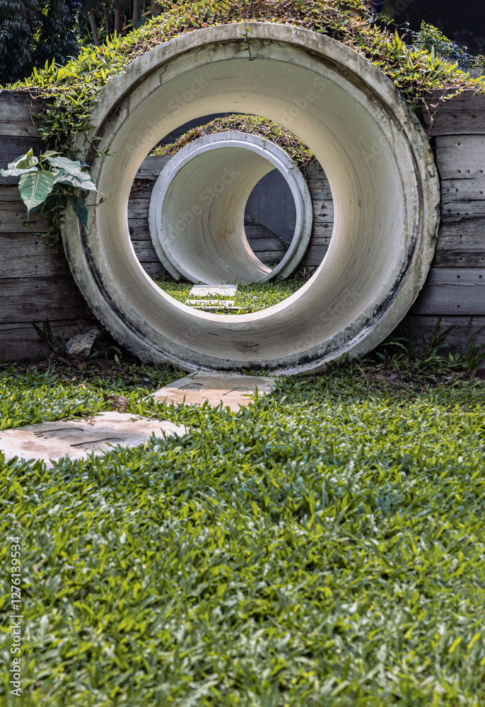 Outdoor playground with The kid's playing tunnel with Grass mound on top in the park for children. Park concrete tunnel made for Children's play as a rabbit, ducking through its numerous burrows.