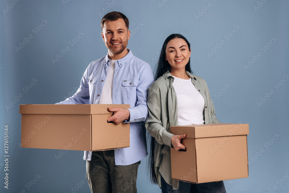 Against blue wall, with boxes, moving. Man and woman are in the studio Against blue wall, with boxes, moving. Man and woman are in the studio
