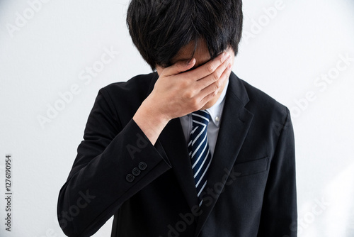 悩み落ち込むスーツを着た男性