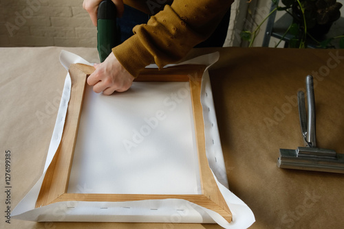 Framer stretching canvas on wooden stretcher bars. 