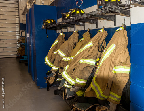 A row of firefighter coats hanging beneath a shelf with fire fighter helmets inside a Florida fire station. 