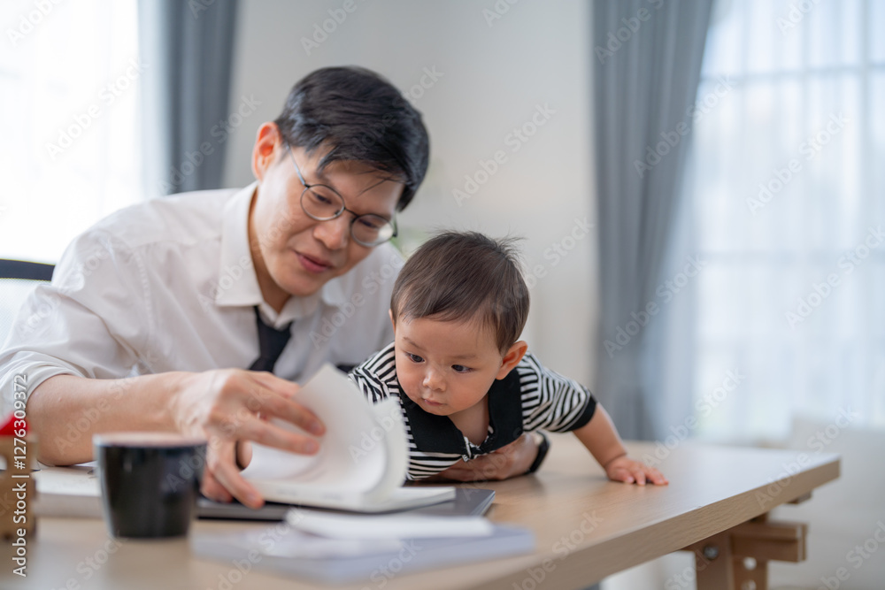 Father engaging with child while working at home office in bright room Father engaging with child while working at home office in bright room