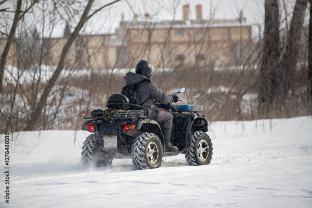 A man is driving an atv in the snow A man is driving an atv in the snow