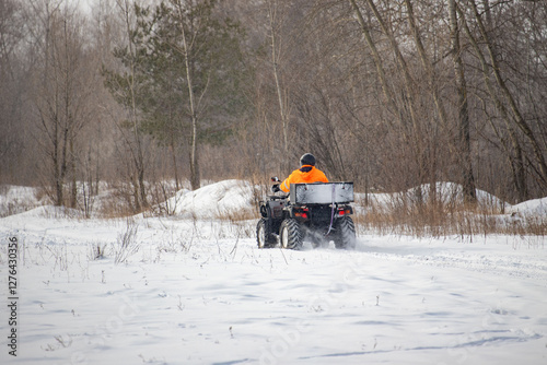 A man is driving a snowmobile in the woods