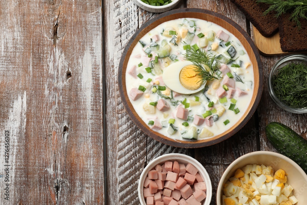 Delicious okroshka soup with kefir in bowl and ingredients on wooden table, flat lay. Space for text Delicious okroshka soup with kefir in bowl and ingredients on wooden table, flat lay. Space for text