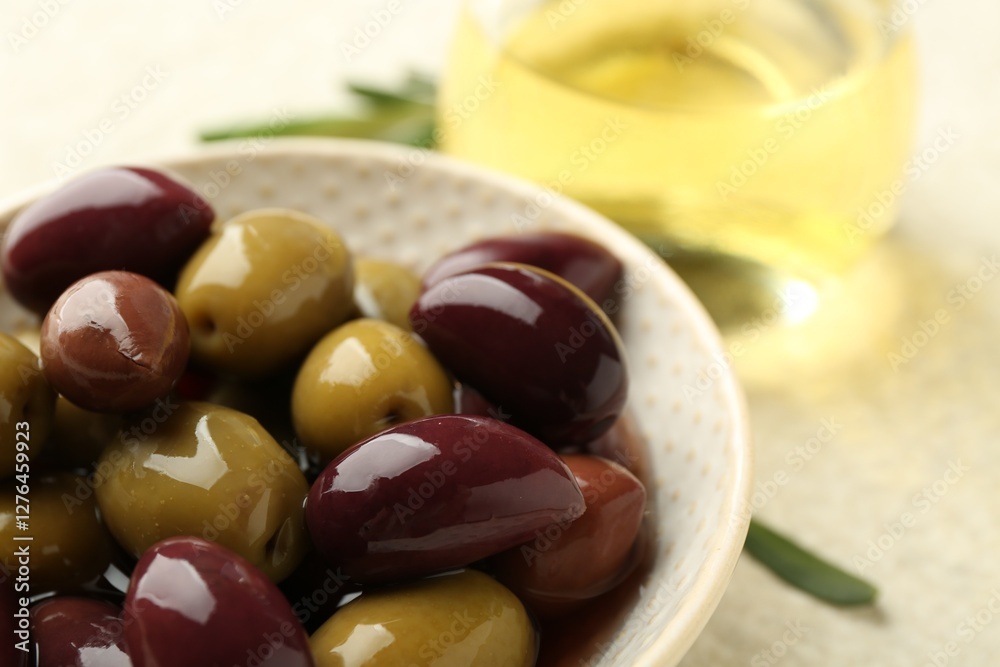 Tasty marinated olives in bowl and oil on beige table, closeup Tasty marinated olives in bowl and oil on beige table, closeup