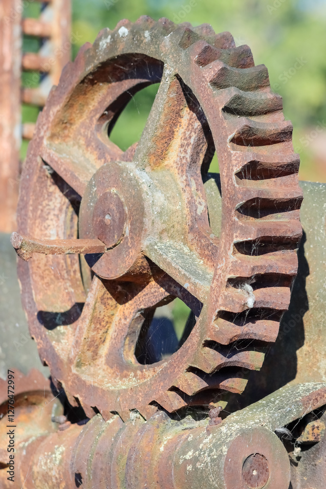 Large, old rusty gear with cobwebs. Detail of decommissioned machine. Worn brown cogwheel in the sunshine in September. Large, old rusty gear with cobwebs. Detail of decommissioned machine. Worn brown cogwheel in the sunshine in September.
