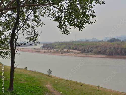 A serene riverscape with a gently flowing river bordered by grassy banks.