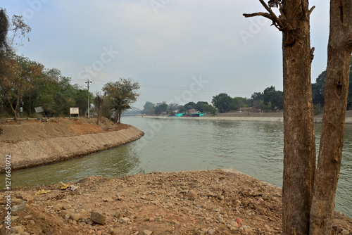 A curved river flanked by trees on both banks flows through a landscape.