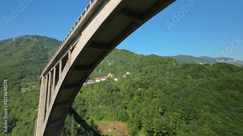 FPV drone orbiting above and under the massive concrete Djurdjevic Bridge over the Tara River, high above the canyon in the mountains of Montenegro