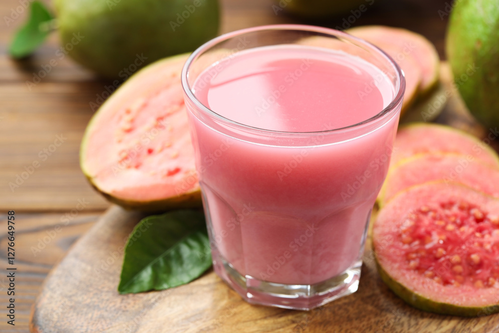 Tasty guava juice in glass, leaf and fruits on wooden table, closeup Tasty guava juice in glass, leaf and fruits on wooden table, closeup