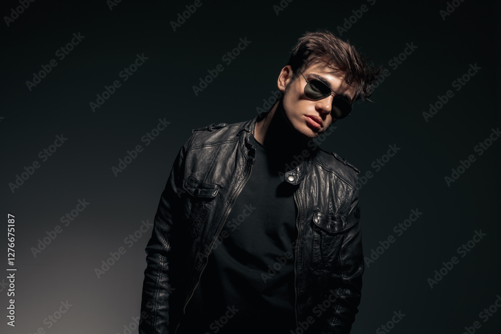 Obraz premium handsome rebel biker in black leather jacket leaning to side