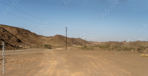 Obraz na płótnie electric line and winding dirt road in desert, near De Riet, Namibia w salonie