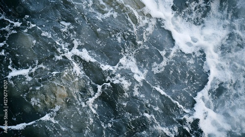 Close-up of dark, foamy water cascading over rocks, creating a dynamic and textured natural scene.