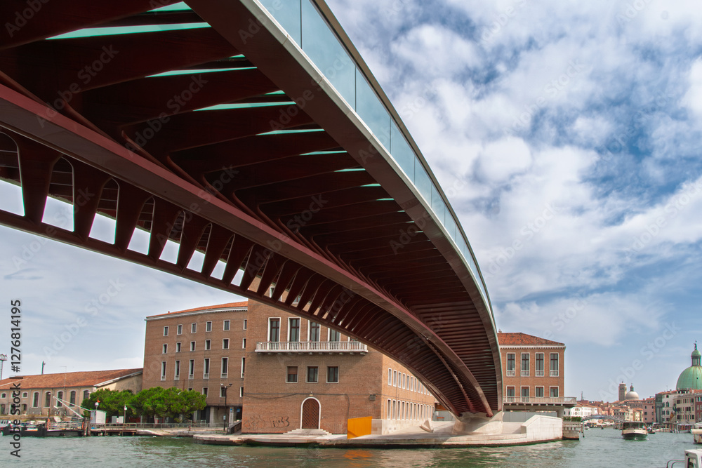 Fototapeta premium Modern constitution bridge spanning over a canal in venice, italy, with historic buildings and a cloudy sky
