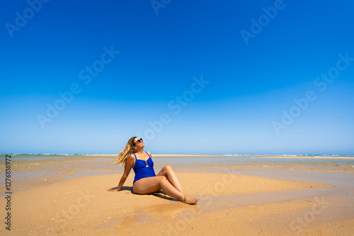 Summer holidays on Armona island in Portugal. Beautiful middle-aged woman sunbathing on sandy idyllic beach photo