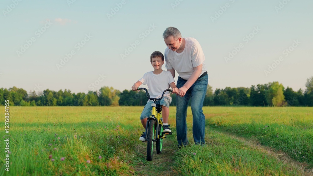 Father teaches his son child to ride bicycle in park. Child is learning to ride bike. Happy family, son dad. Child rides bicycle for first time. Boy kid dream of traveling by bike. Dad helps child. Father teaches his son child to ride bicycle in park. Child is learning to ride bike. Happy family, son dad. Child rides bicycle for first time. Boy kid dream of traveling by bike. Dad helps child.