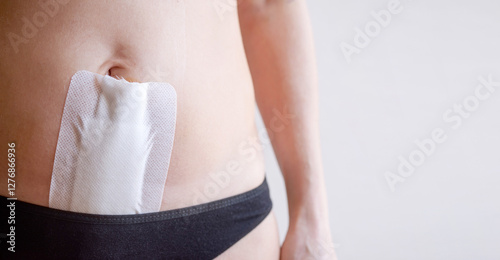 Woman recovering abdomen after gynecological operation hysterectomy or laparotomy, covered with medical white tape, close-up, copy space