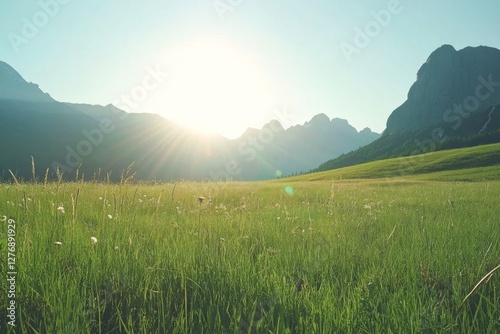 Obraz na płótnie A breathtaking sunrise casts its golden light over an expansive green field, while majestic mountains rise proudly in the serene valley below w salonie