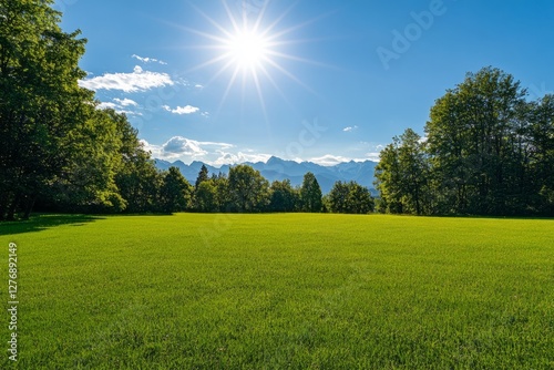 Obraz na płótnie Bright sun shines over green field with mountains in the distance on a clear day in the countryside w salonie