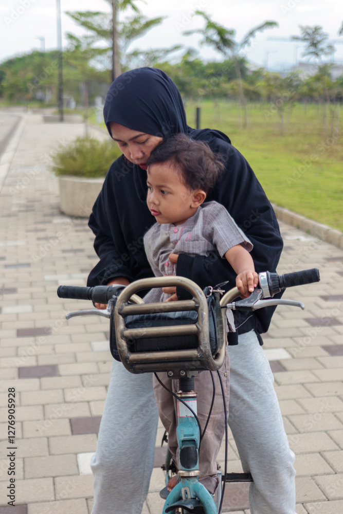 Obraz premium Mother Teaching Her Child to Ride a Bicycle Outdoors