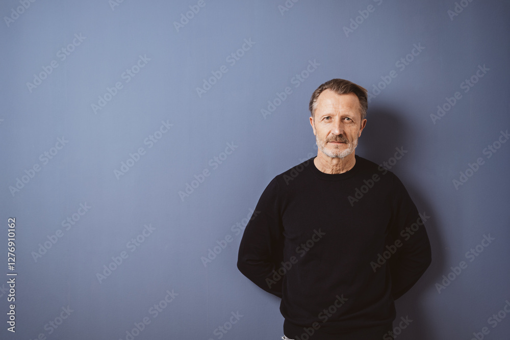 Obraz premium Serious senior man in black sweater against blue background