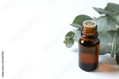 Eucalyptus essential oil in a glass bottle with green eucalyptus leaves on a white background. Aromatherapy concept. Spa. Natural organic ingredients for cosmetics and body care. photo